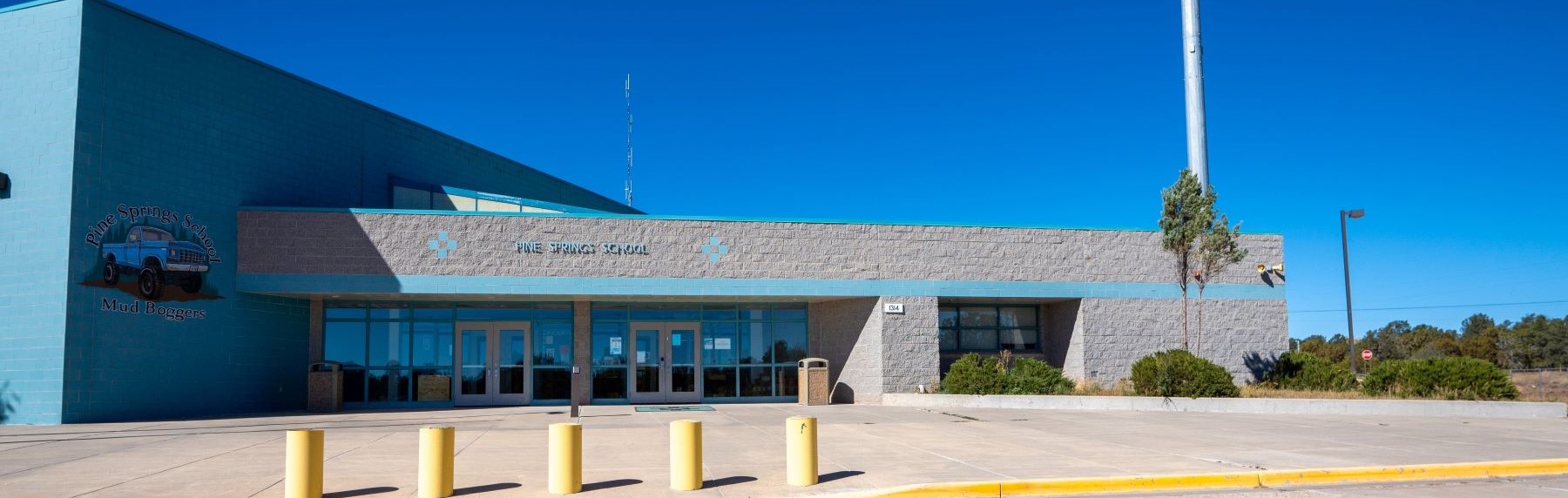 The entrance to Pine Springs Day School, blue brick with mud boggers logo painted on the exterior.